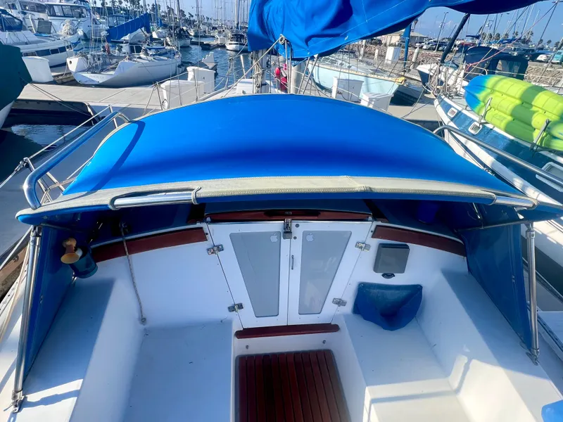 Slide: The Image of 1983 Catalina 36 sailboat cockpit with blue canopy, docked in a marina. - 18
