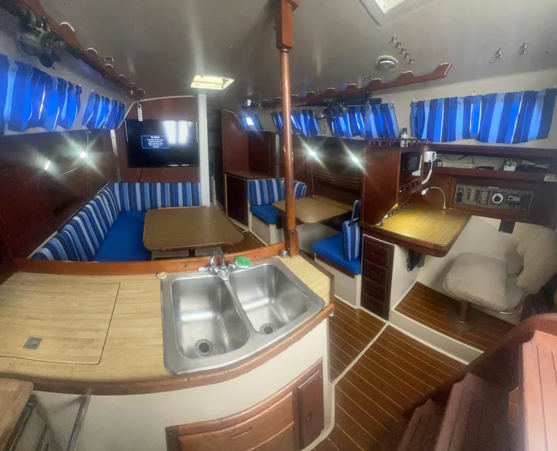 Slide: The Image of Interior of a 1983 Catalina 36 sailboat with blue-striped seating and wooden finishes. - 28