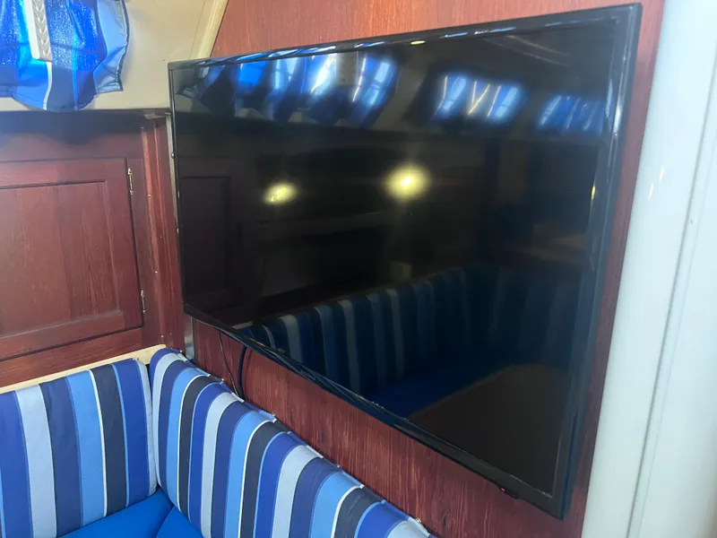 Slide: The Image of Flat-screen TV in a 1983 Catalina 36 yacht interior with striped seating. - 30