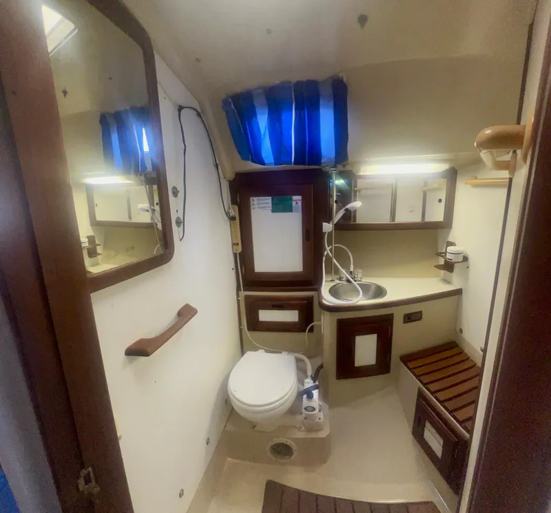 Slide: The Image of 1983 Catalina 36 yacht bathroom with toilet, sink, mirror, and storage cabinets. - 32
