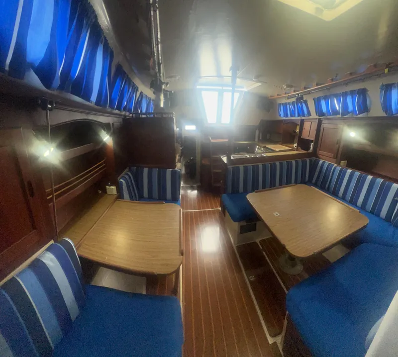 Slide: The Image of Interior of 1983 Catalina 36 sailboat with blue-striped seating and wooden tables. - 34