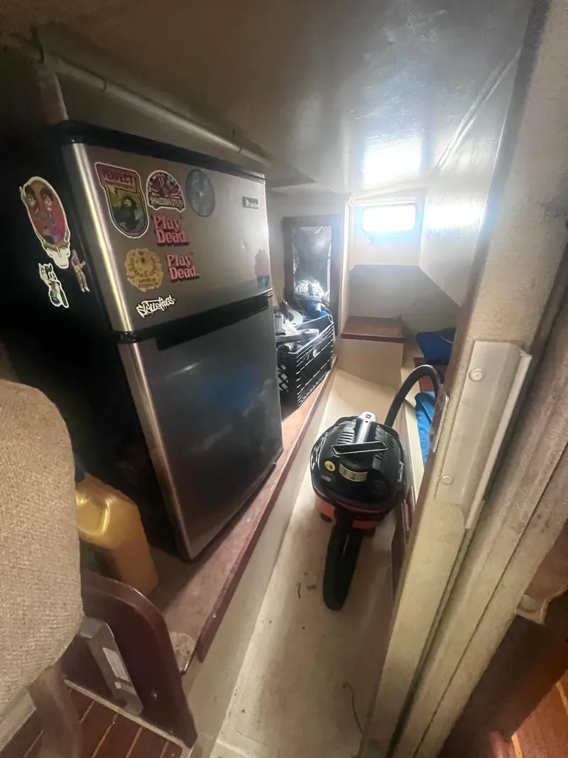 Slide: The Image of 1983 Catalina 36 interior with mini fridge, vacuum, and storage space. - 36