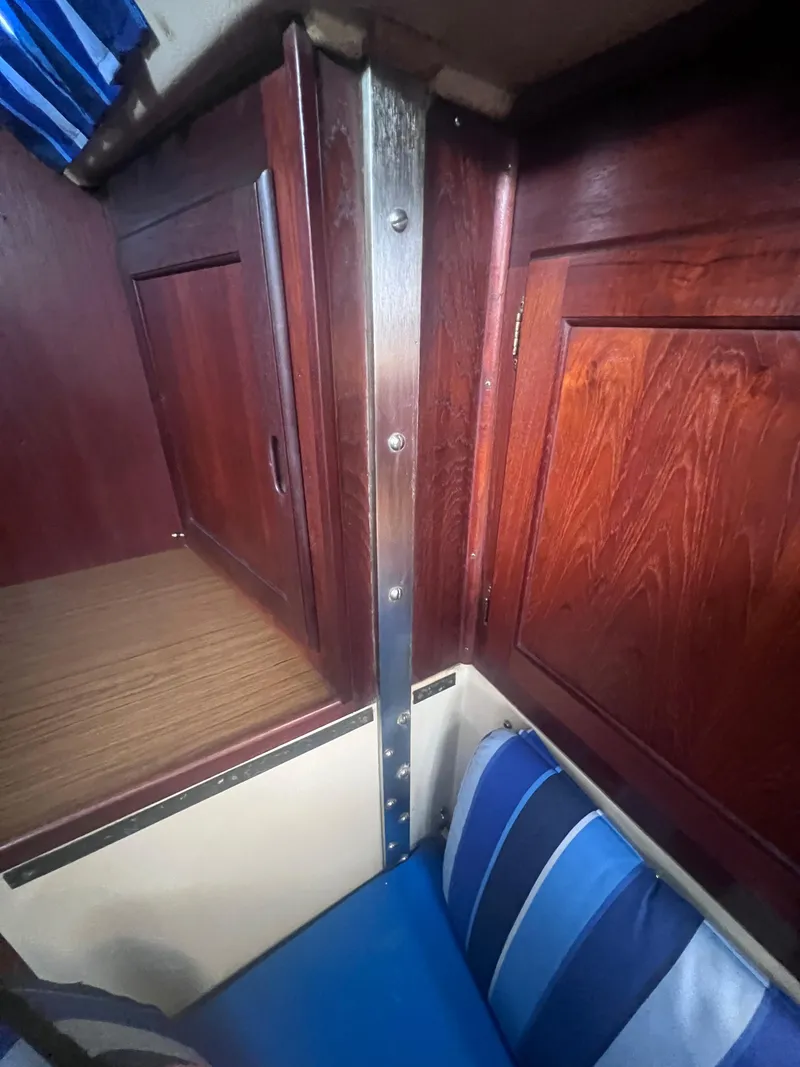 Slide: The Image of Interior of 1983 Catalina 36 sailboat with wooden cabinets and blue-striped cushions. - 40