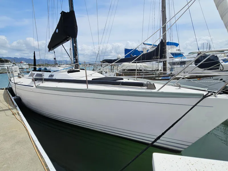 Slide: The Image of 1987 Express 37 sailboat docked at marina, clear sky, calm waters. - 0