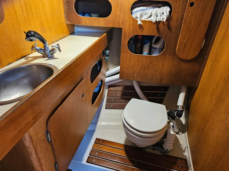 Slide: The Image of 1987 Express 37 boat bathroom with wooden cabinets, sink, and marine toilet. - 16