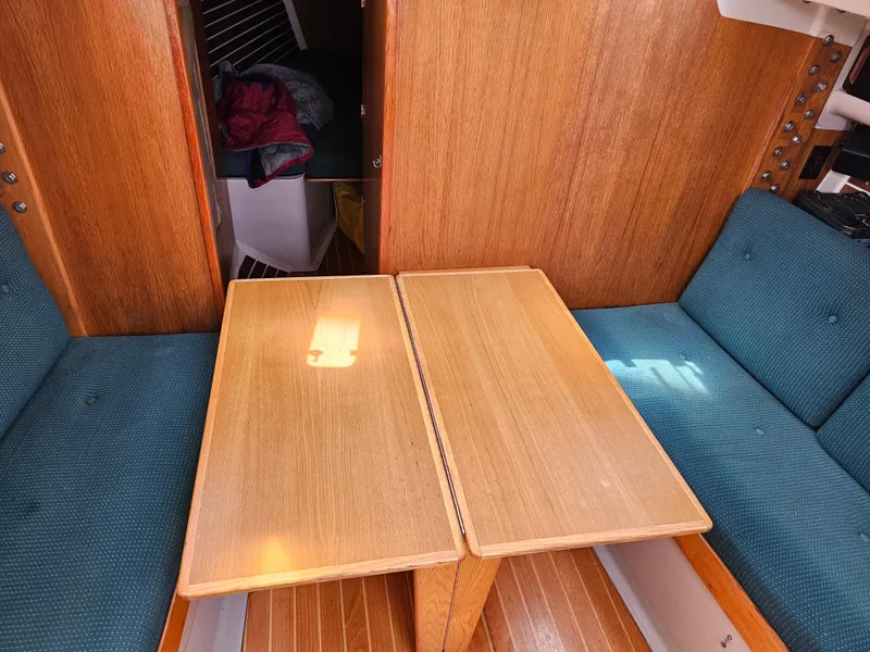 Slide: The Image of Interior of 1987 Express 37 sailboat with wooden table and blue cushioned seating. - 9