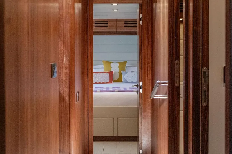 Slide: The Image of Interior hallway view of 2022 Sirena 58 Flybridge yacht, featuring wooden doors and cozy bedroom. - 18