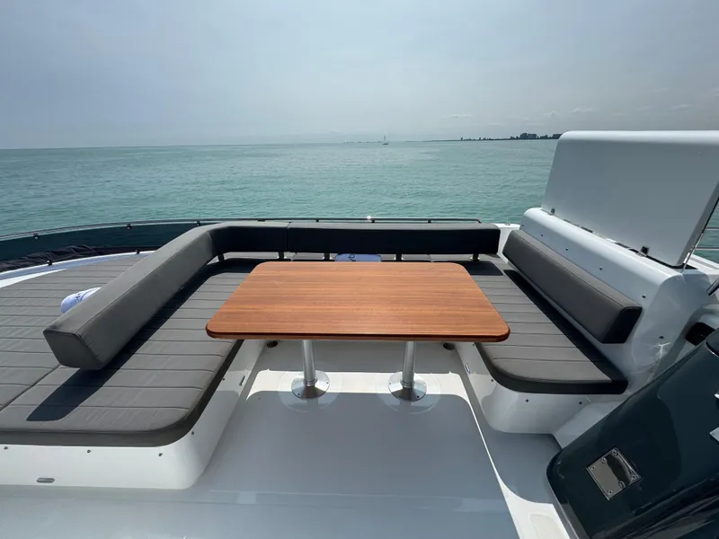 Slide: The Image of Sirena 58 Flybridge 2022 yacht deck with seating and table, overlooking the ocean. - 34