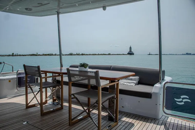 Slide: The Image of Sirena 58 Flybridge 2022 yacht deck with dining area overlooking serene ocean view. - 9