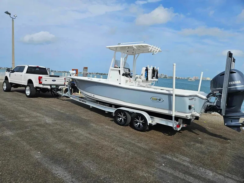 Slide: The Image of 2020 Sea Hunt BX 25 BR boat on trailer, towed by a white truck near the water. - 18