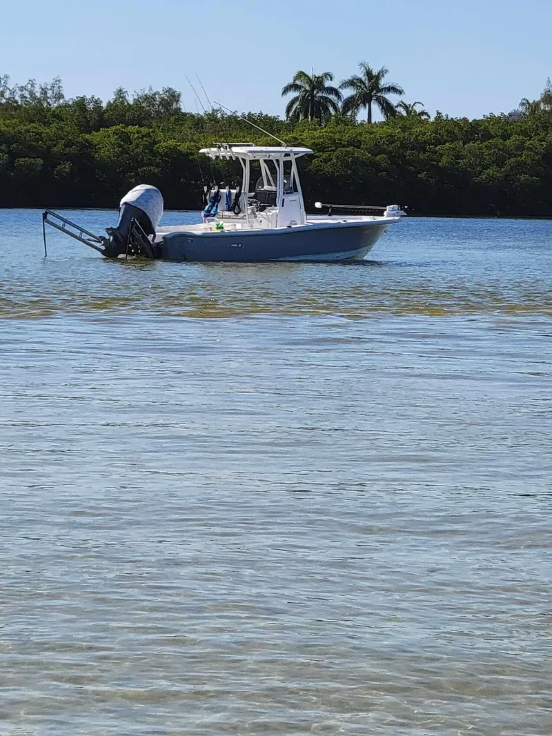 Slide: The Image of 2020 Sea Hunt BX 25 BR boat on calm water with lush greenery background. - 2