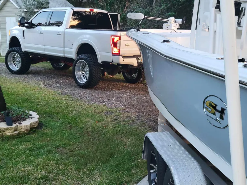 Slide: The Image of White truck towing 2020 Sea Hunt BX 25 BR boat on a grassy driveway. - 20