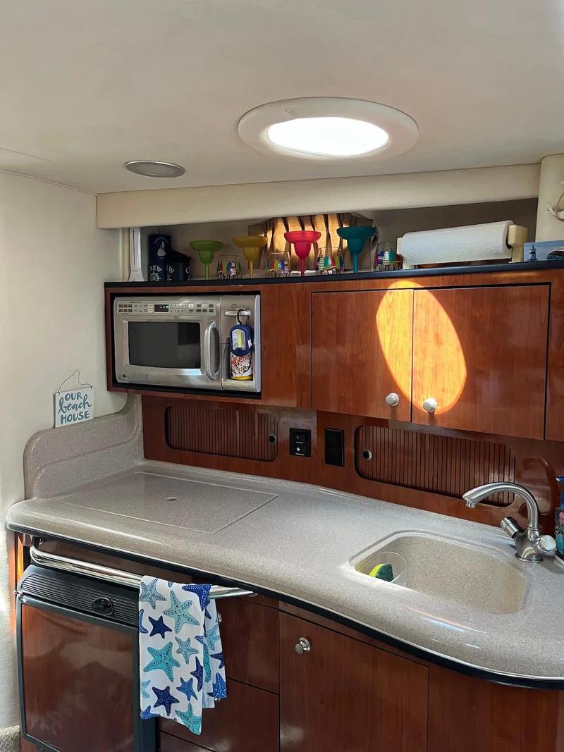 Slide: The Image of 2006 Sea Ray 320 Sundancer kitchen with microwave, sink, and wooden cabinets. - 7