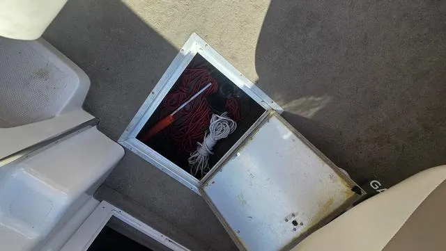 Slide: The Image of Open storage compartment on 2001 Reinell 240 C boat, containing ropes and a tool. - 16