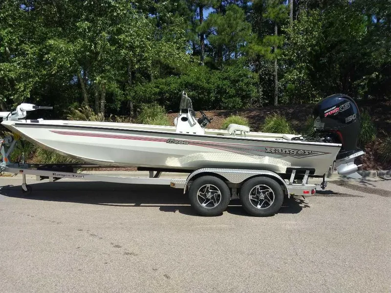The Image of 2024 Ranger RB200 boat on trailer, parked outdoors, surrounded by trees. - 0