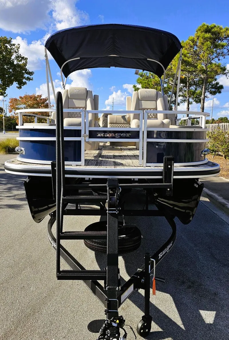 Slide: The Image of 2024 Ranger Reata 223F pontoon boat with canopy, parked on a trailer. - 6