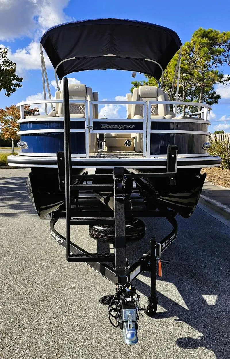 Slide: The Image of 2024 Ranger Reata 223F pontoon boat on trailer, parked outdoors. - 7