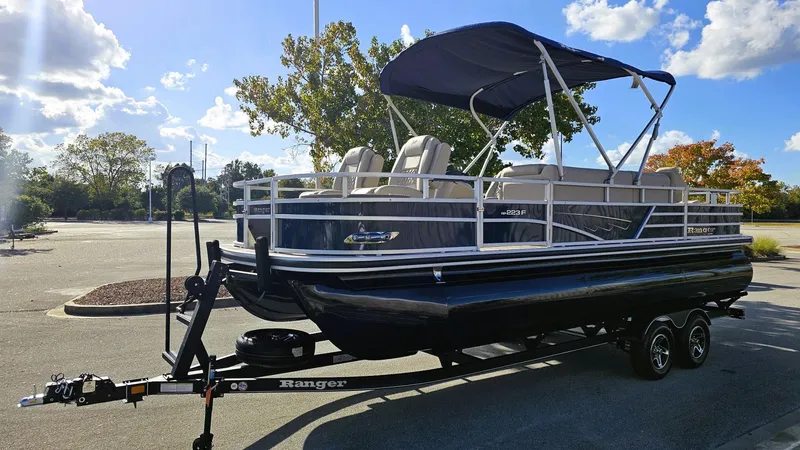 Slide: The Image of 2024 Ranger Reata 223F pontoon boat on trailer in sunny parking lot. - 9