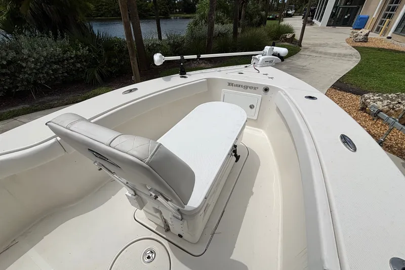 Slide: The Image of 2024 Ranger 2600 Bay boat interior with seating and trolling motor, near a scenic waterway. - 7