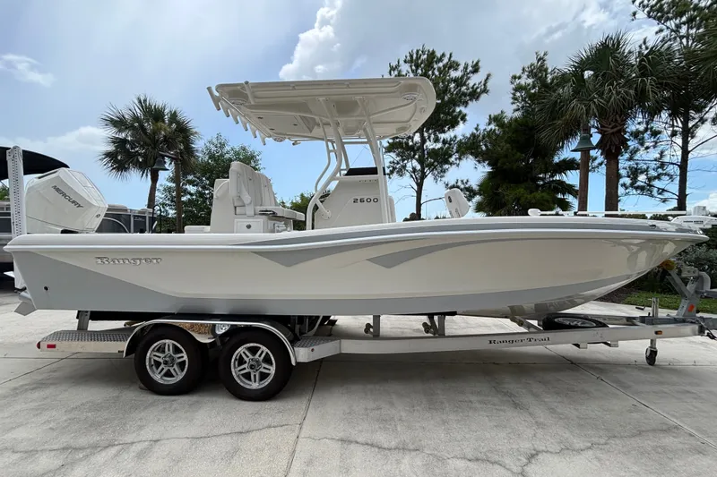 Slide: The Image of 2024 Ranger 2600 Bay boat on trailer, parked outdoors with palm trees in background. - 1
