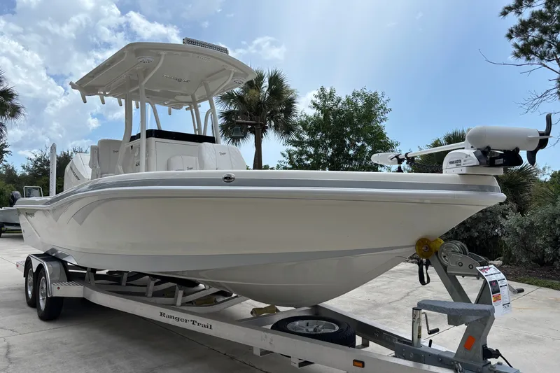The Image of 2024 Ranger 2600 Bay boat on trailer, parked outdoors under a cloudy sky. - 0