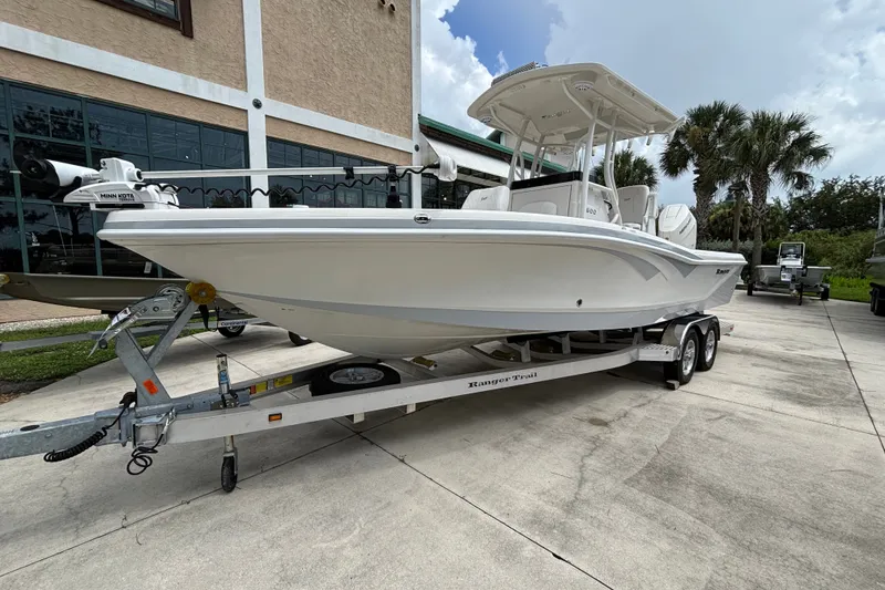 Slide: The Image of 2024 Ranger 2600 Bay boat on trailer, parked outdoors near palm trees. - 6