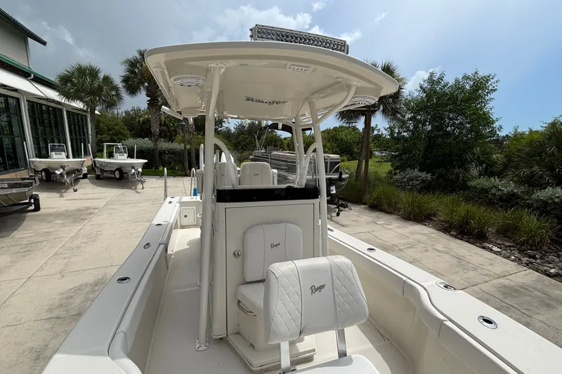 Slide: The Image of 2024 Ranger 2600 Bay boat with T-top, parked outdoors near greenery. - 9