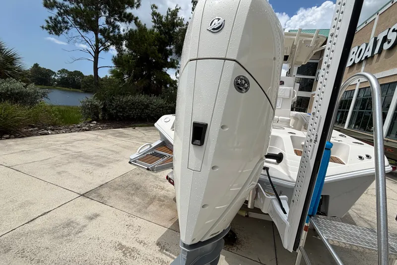 Slide: The Image of 2024 Ranger 2600 Bay boat with powerful outboard motor, displayed outdoors near a lake. - 16
