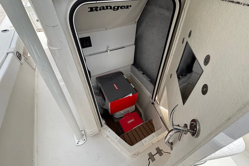 Slide: The Image of 2024 Ranger 2600 Bay boat storage compartment with boxes and equipment inside. - 11
