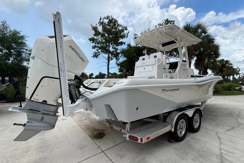 Slide: The Image of 2024 Ranger 2600 Bay boat with Mercury engine on trailer, parked outdoors. - 2