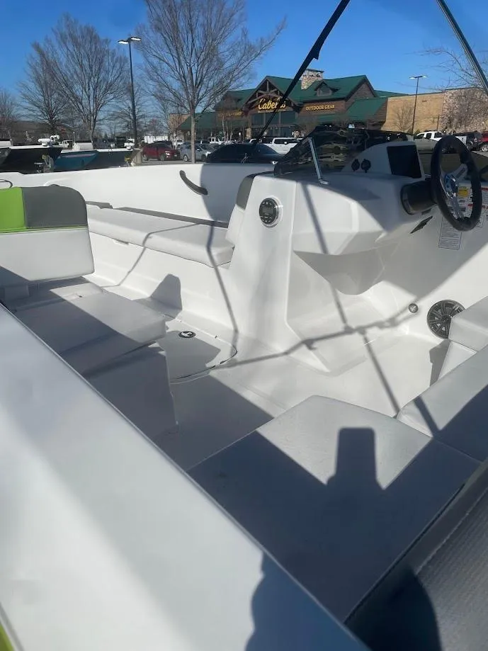 Slide: The Image of 2024 Tahoe T18 boat interior with seating and steering wheel, parked outdoors. - 2