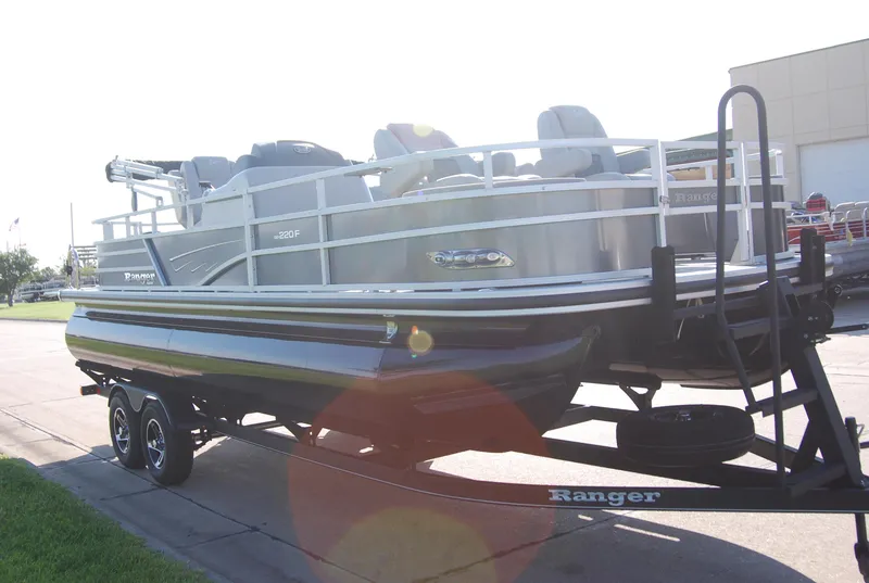 Slide: The Image of 2024 Ranger Reata 220F pontoon boat on trailer, parked outdoors. - 2