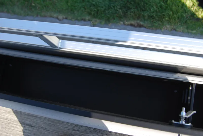 Slide: The Image of 2024 Ranger Reata 220F storage compartment with metal railing and green grass background. - 9