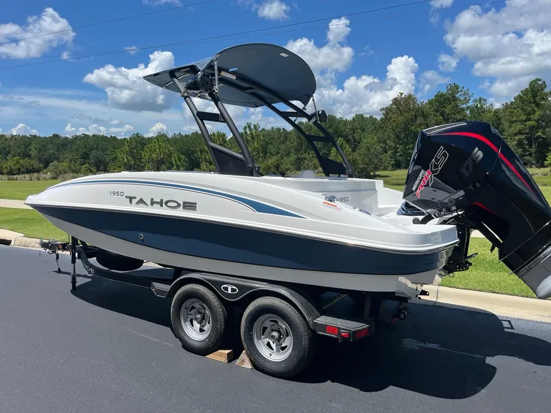 Slide: The Image of 2024 Tahoe 1950 boat on trailer, parked outdoors under a clear blue sky. - 2
