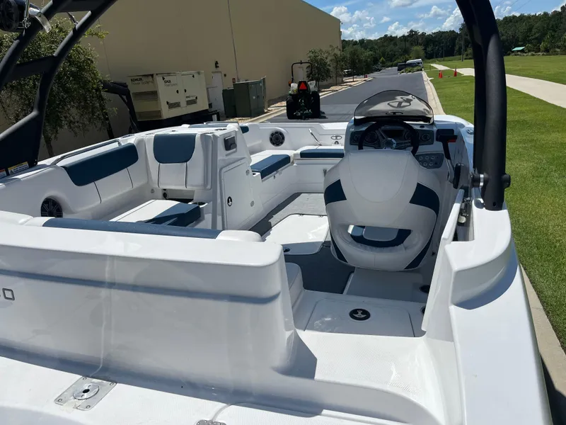 Slide: The Image of 2024 Tahoe 1950 boat interior with seating and steering console, parked outdoors. - 3