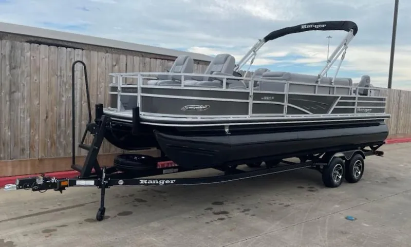 Slide: The Image of 2024 Ranger Reata 220F pontoon boat on trailer, parked outdoors. - 0