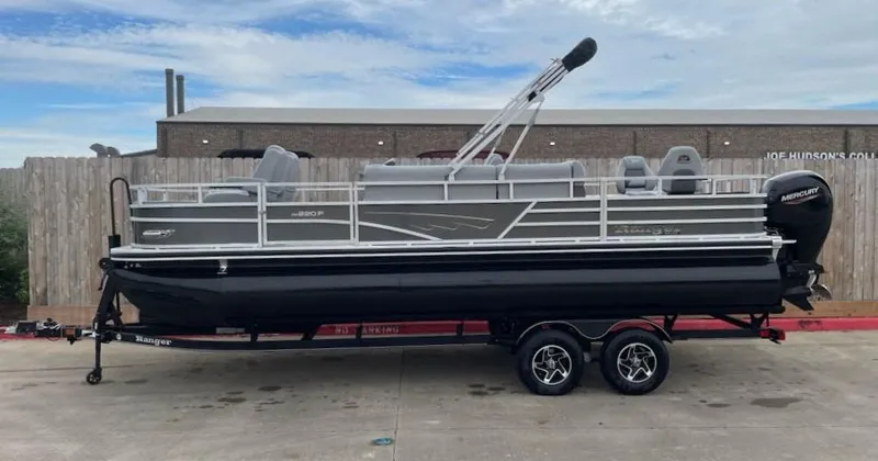 Slide: The Image of 2024 Ranger Reata 220F pontoon boat on trailer, parked outdoors. - 1