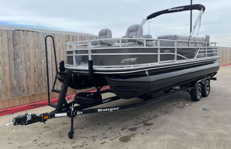 Slide: The Image of 2024 Ranger Reata 220F pontoon boat on trailer, parked outdoors. - 0