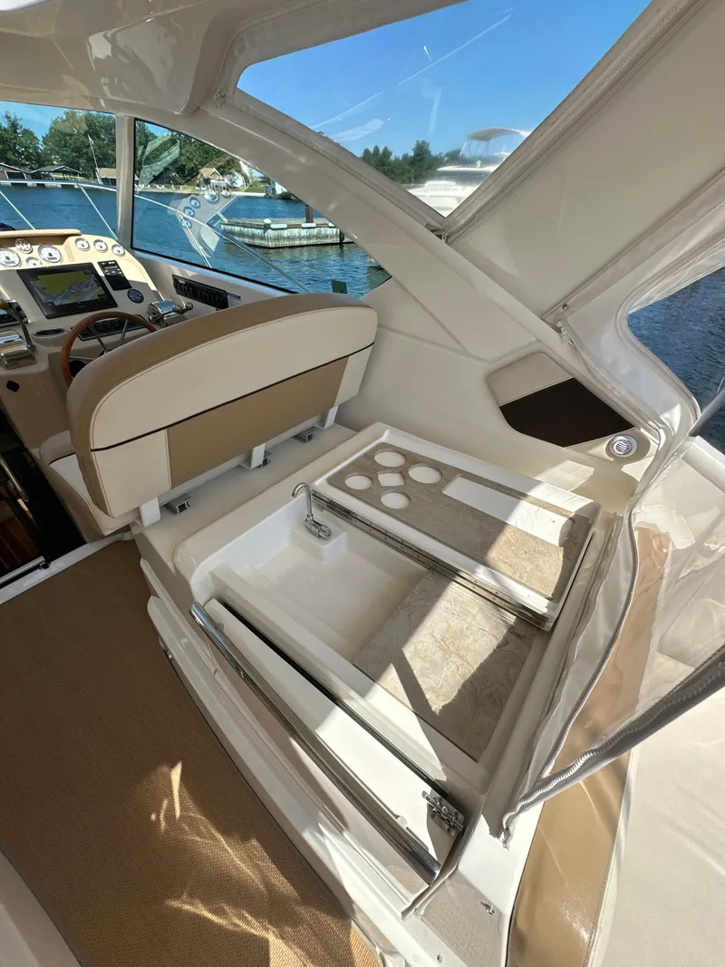 Slide: The Image of 2014 Tiara Yachts 3100 Coronet interior with seating and storage, docked by the water. - 11