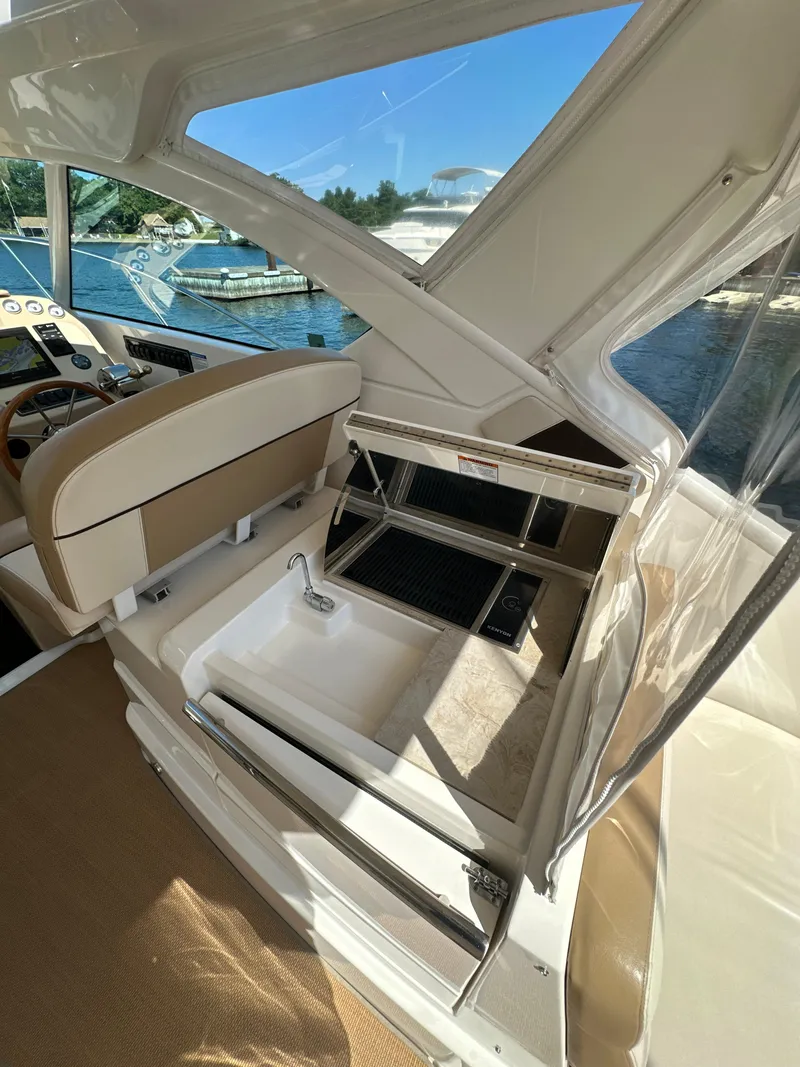 Slide: The Image of 2014 Tiara Yachts 3100 Coronet interior with sink and seating, docked by the water. - 12