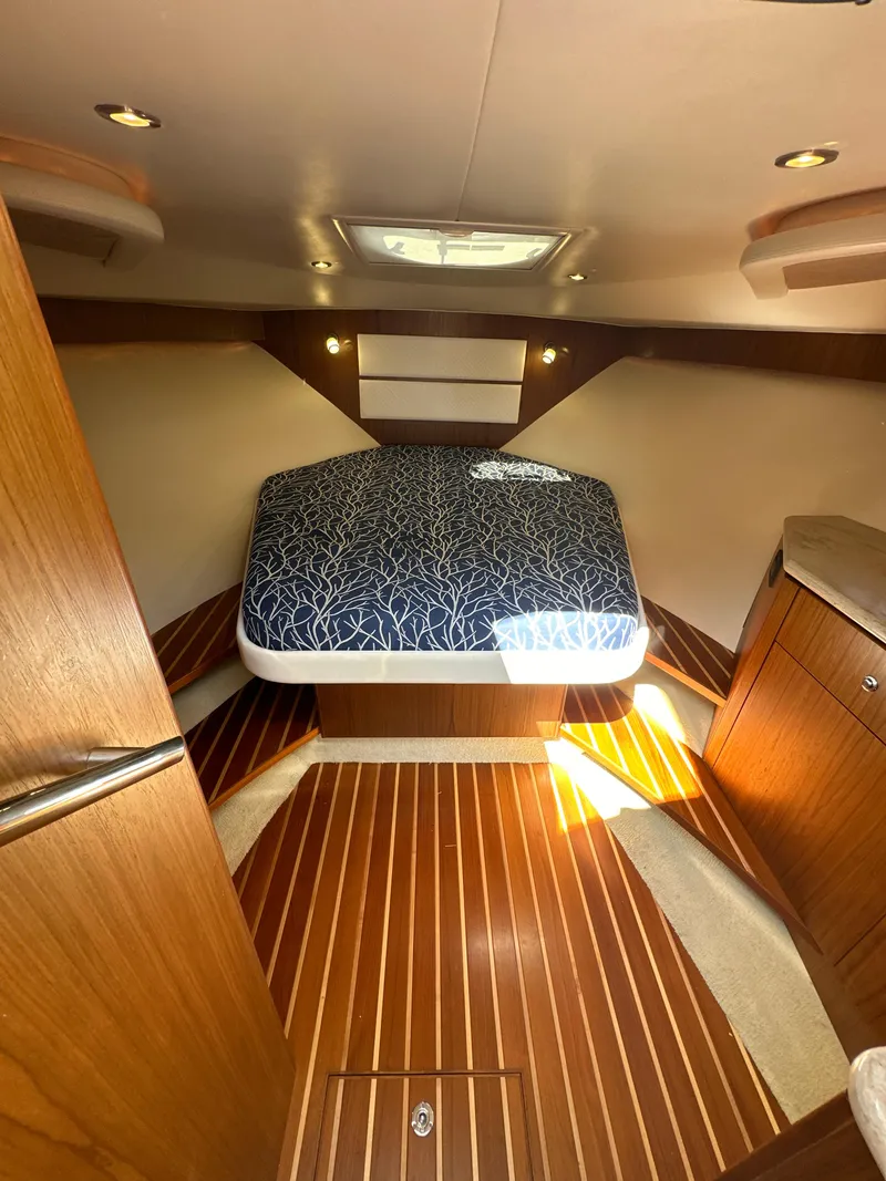 Slide: The Image of 2014 Tiara Yachts 3100 Coronet cabin with bed, wood flooring, and modern lighting. - 17