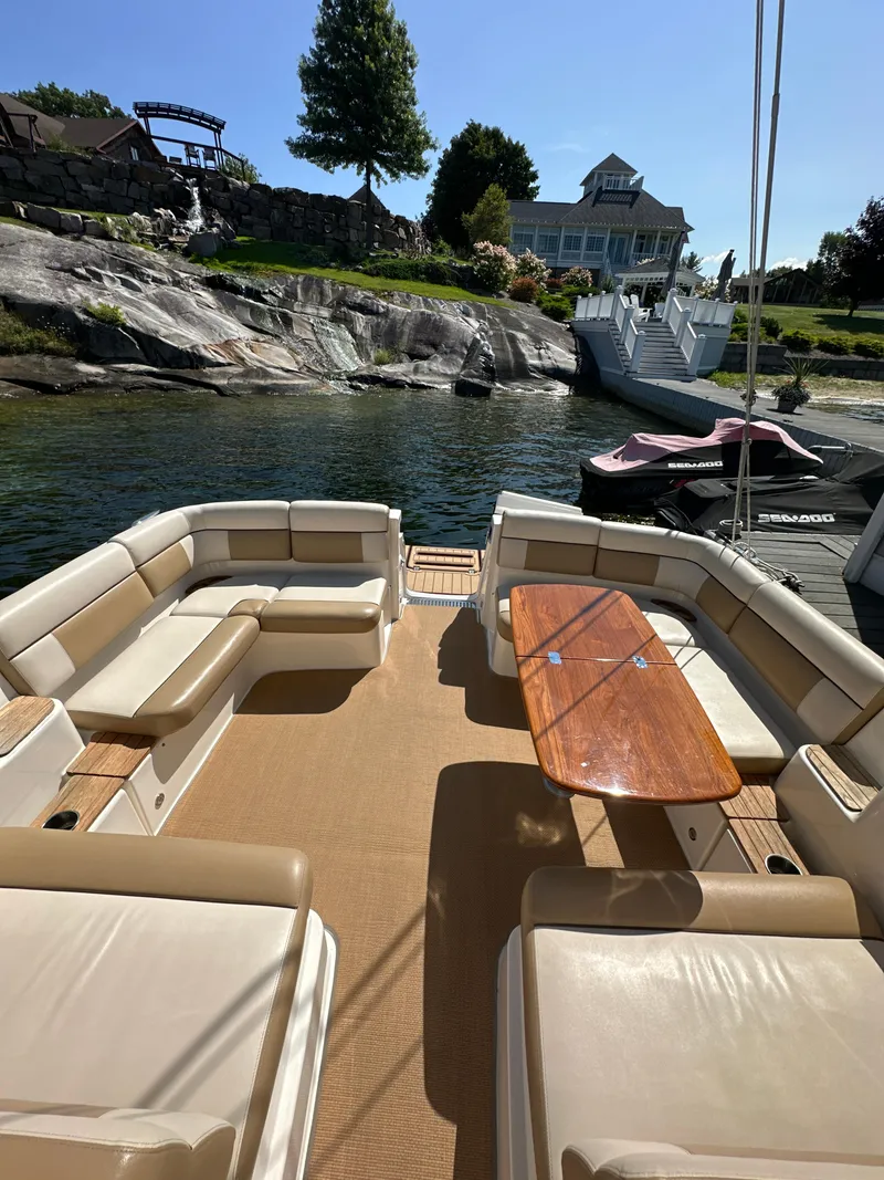 Slide: The Image of 2014 Tiara Yachts 3100 Coronet with spacious seating and wooden table, docked by a scenic shoreline. - 8