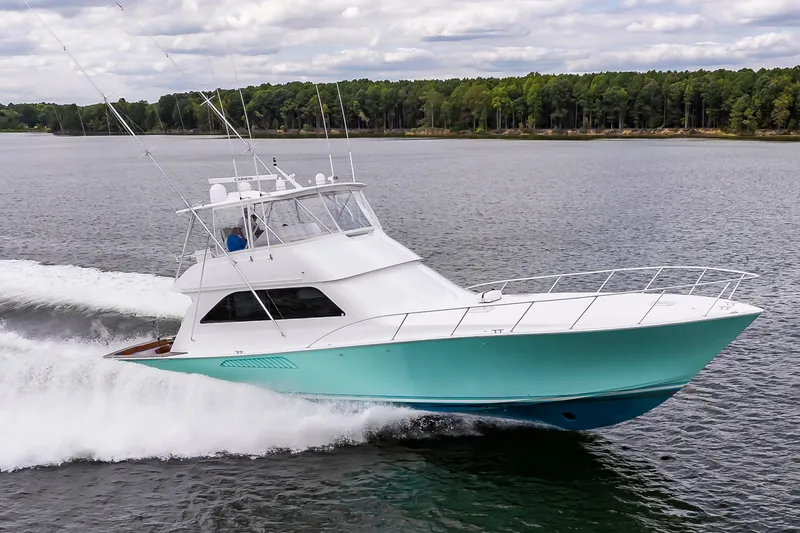 Slide: The Image of 2003 Viking 61 Convertible yacht cruising on a lake with forested shoreline. - 0