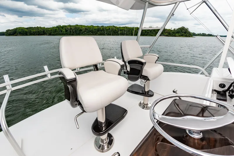 Slide: The Image of Luxury seating on 2003 Viking 61 Convertible yacht, overlooking serene water and lush greenery. - 14