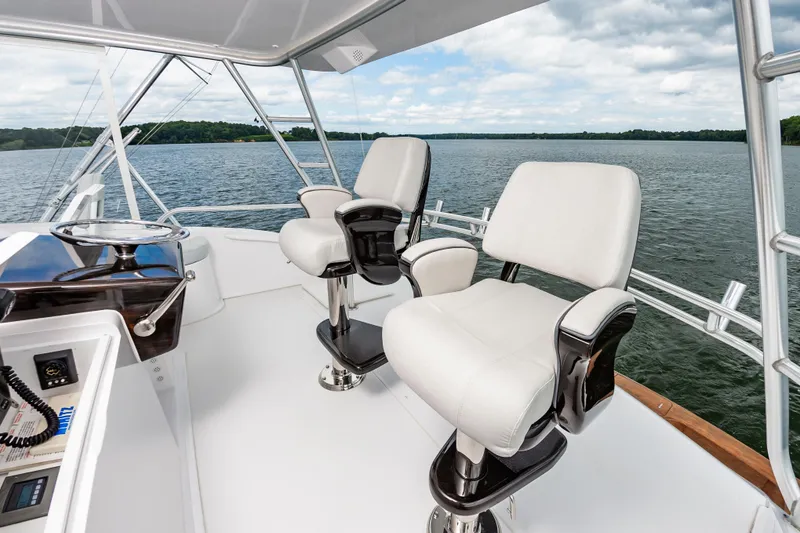 Slide: The Image of 2003 Viking 61 Convertible yacht helm with two white captain chairs on a serene lake. - 15