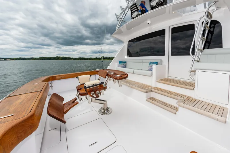 Slide: The Image of 2003 Viking 61 Convertible yacht deck with seating and fishing chair, under cloudy skies. - 23