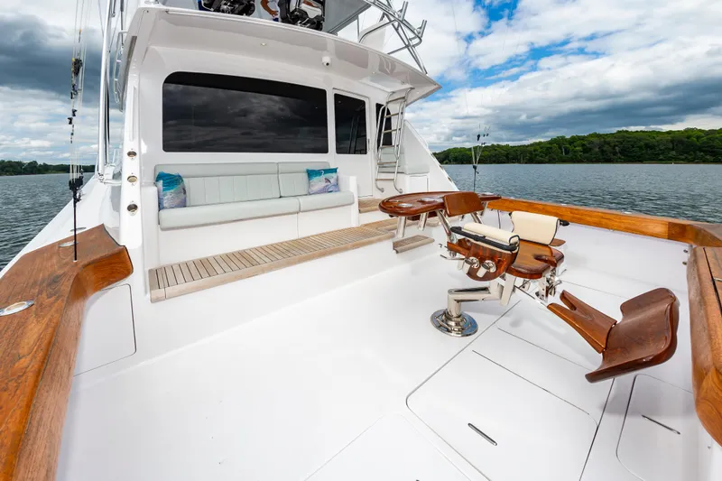 Slide: The Image of 2003 Viking 61 Convertible yacht deck with seating and fishing chair on a calm lake. - 24