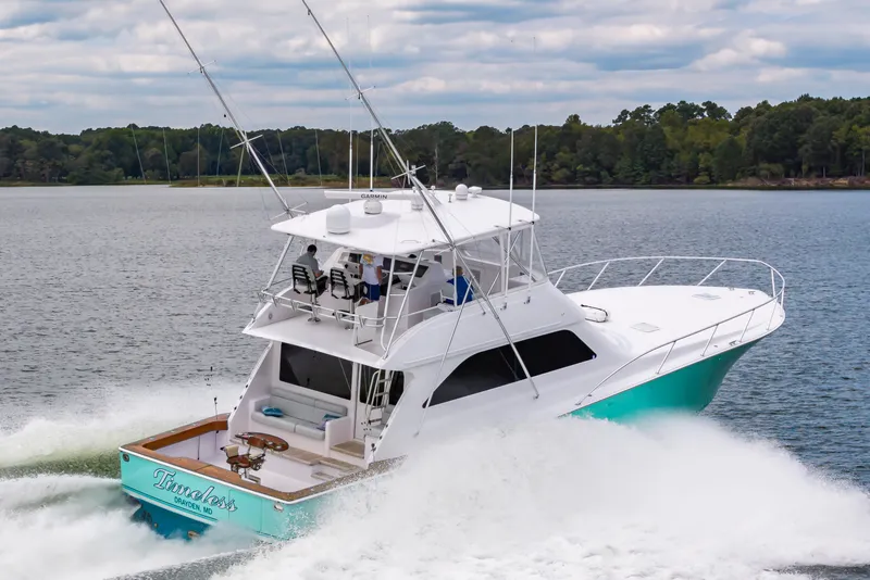 Slide: The Image of 2003 Viking 61 Convertible yacht cruising on a lake with lush forest backdrop. - 6