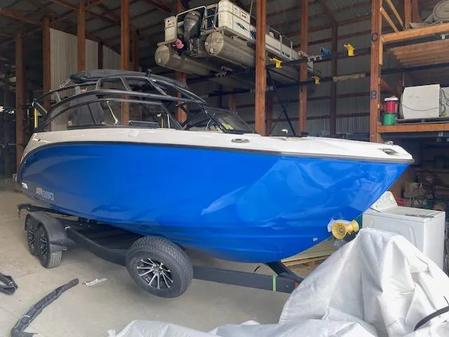 The Image of 2025 Yamaha Boats AR250 in storage, vibrant blue hull on trailer. - 0