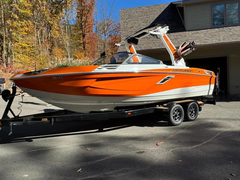Slide: The Image of 2023 Centurion Ri230 boat in vibrant orange on a trailer, parked outdoors. - 12